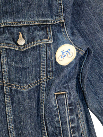 Unisex Jeans Jacke mit kleine Patch auf der ein Fahrrad gestickt ist auf Seite der linken Brusttasche