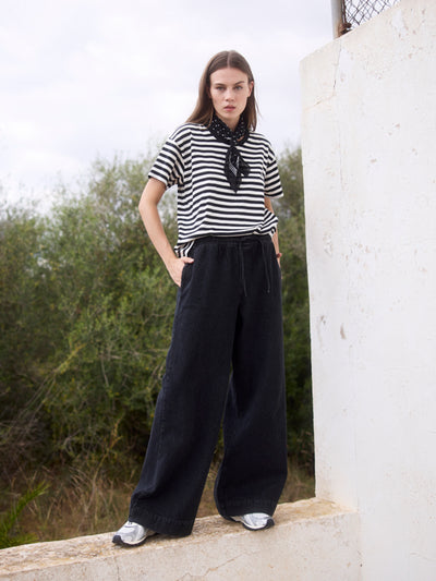 Damen Black Denim Wide Leg aus Bio-Baumwolle in der Frontansicht, kombiniert mit gestreiftem Shirt.