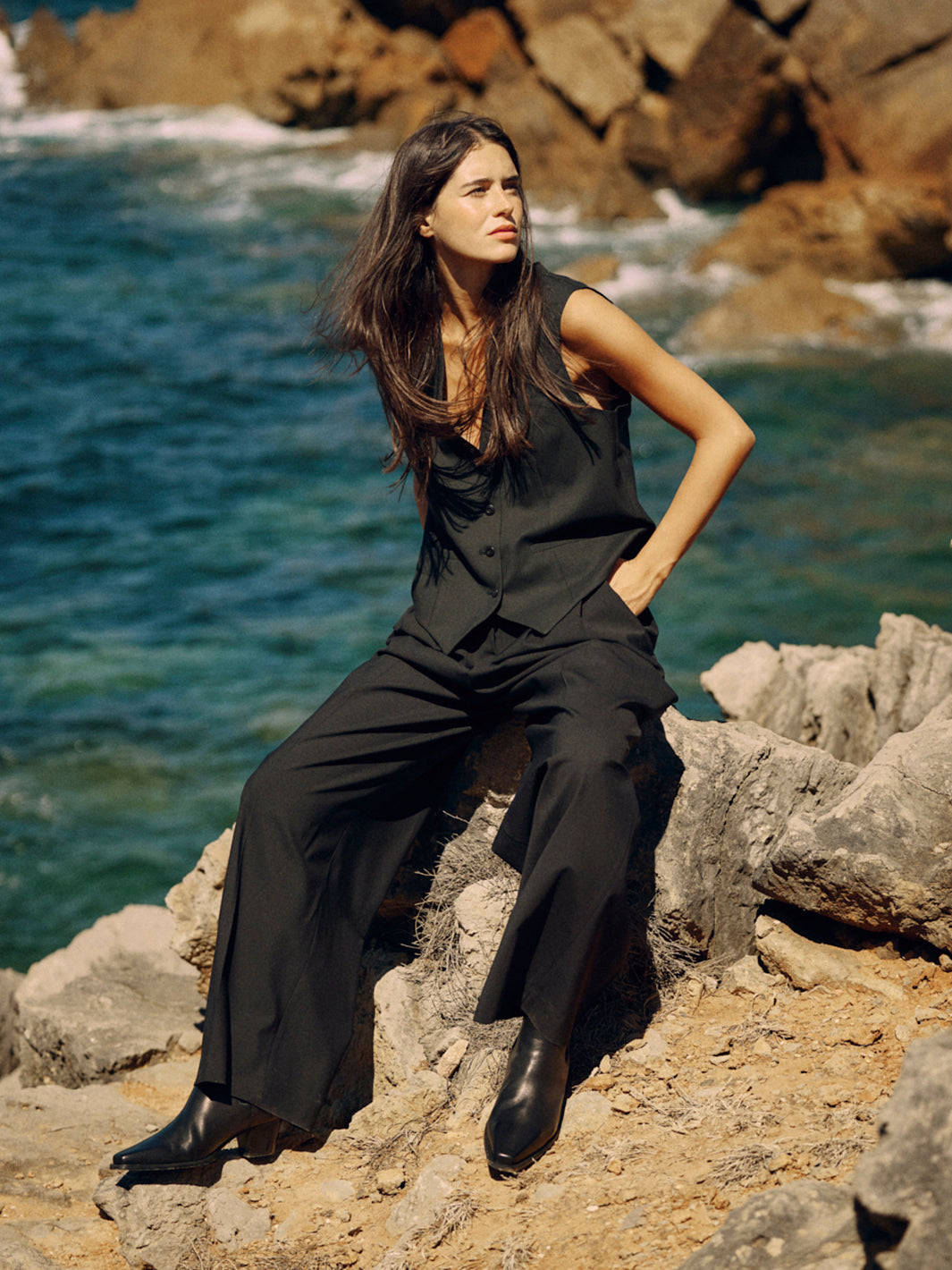 Nachhaltige Damen Weste in Schwarz aus Wolle von WOTE - modern & fair gefertigt in Portugal (Model sitzend Front mit langer Hose)