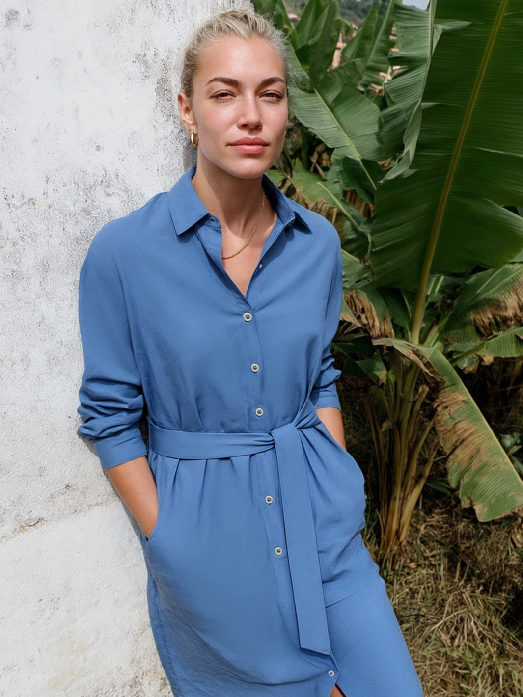 Frau trägt ein blaues Midi-Hemdblusenkleid aus Organic Cotton mit Bindegürtel und Knopfleiste.