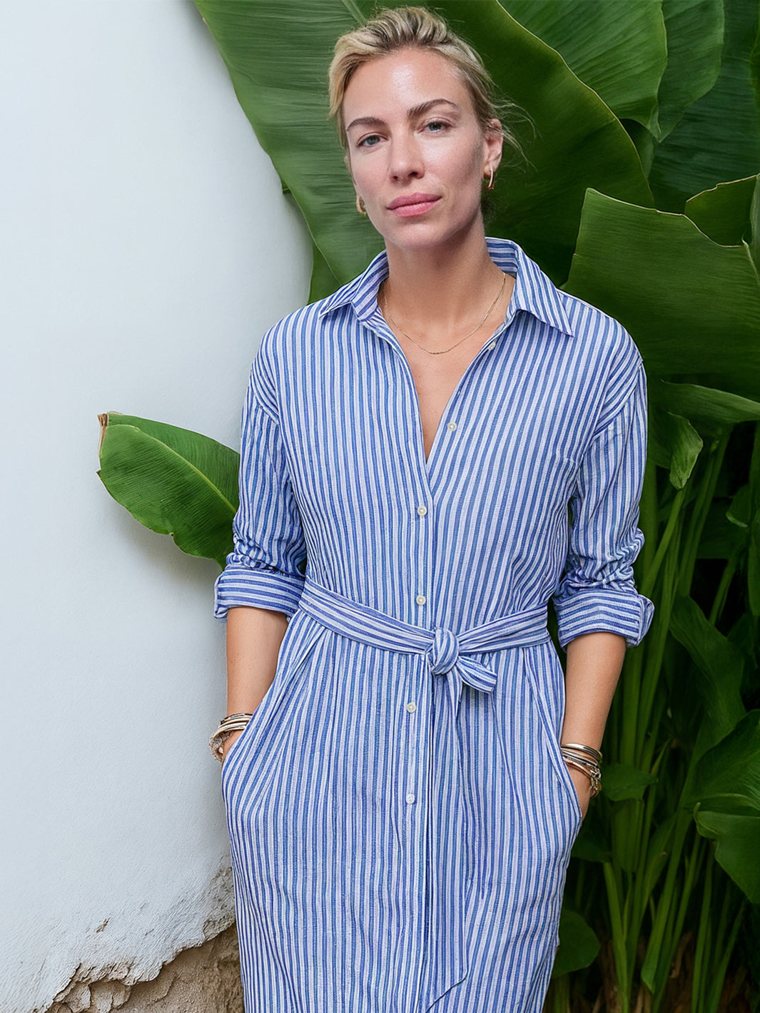 Frau trägt ein blau-weiß gestreiftes Midi-Hemdblusenkleid aus Organic Cotton, frontal aufgenommen mit geknotetem Taillenband und hochgekrempelten Ärmeln