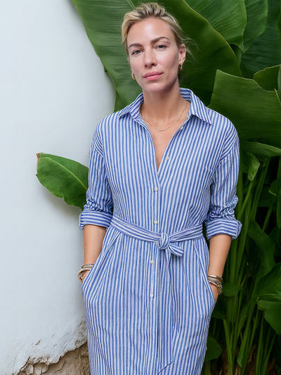 Frau trägt ein blau-weiß gestreiftes Midi-Hemdblusenkleid aus Organic Cotton, frontal aufgenommen mit geknotetem Taillenband und hochgekrempelten Ärmeln