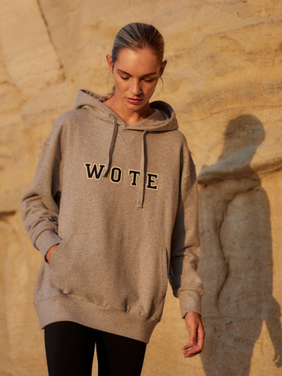 Model trägt einen grauen WOTE Logo Hoodie aus Organic Cotton, frontal mit Händen in der Tasche.