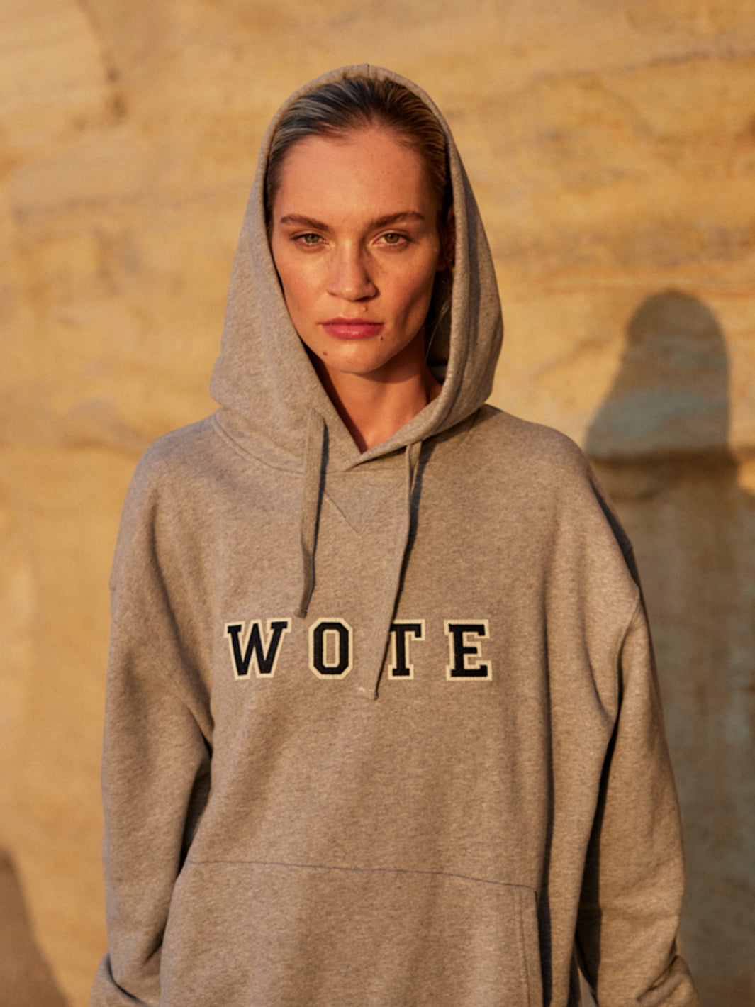 Model trägt einen grauen WOTE Logo Hoodie aus Organic Cotton, frontal im warmen Abendlicht.