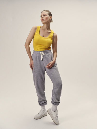 Geripptes Damen Tank Top in Gelb, enganliegende Passform mit tieferen Rundhalsausschnitt aus 96% Bio-Baumwolle und 4% Elasthan made in Portugal von WOTE - Frontansicht Model stehend mit Sweatpants in Grau Melange