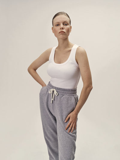 Geripptes Damen Tank Top mit tiefen Rundhalsausschnitt in Weiß aus 96% Bio-Baumwolle und 4% Elasthan, fair und nachhaltig in Portugal produziert von WOTE - Frontansicht mit Model im Studio mit Sweathose in Grau-Melange